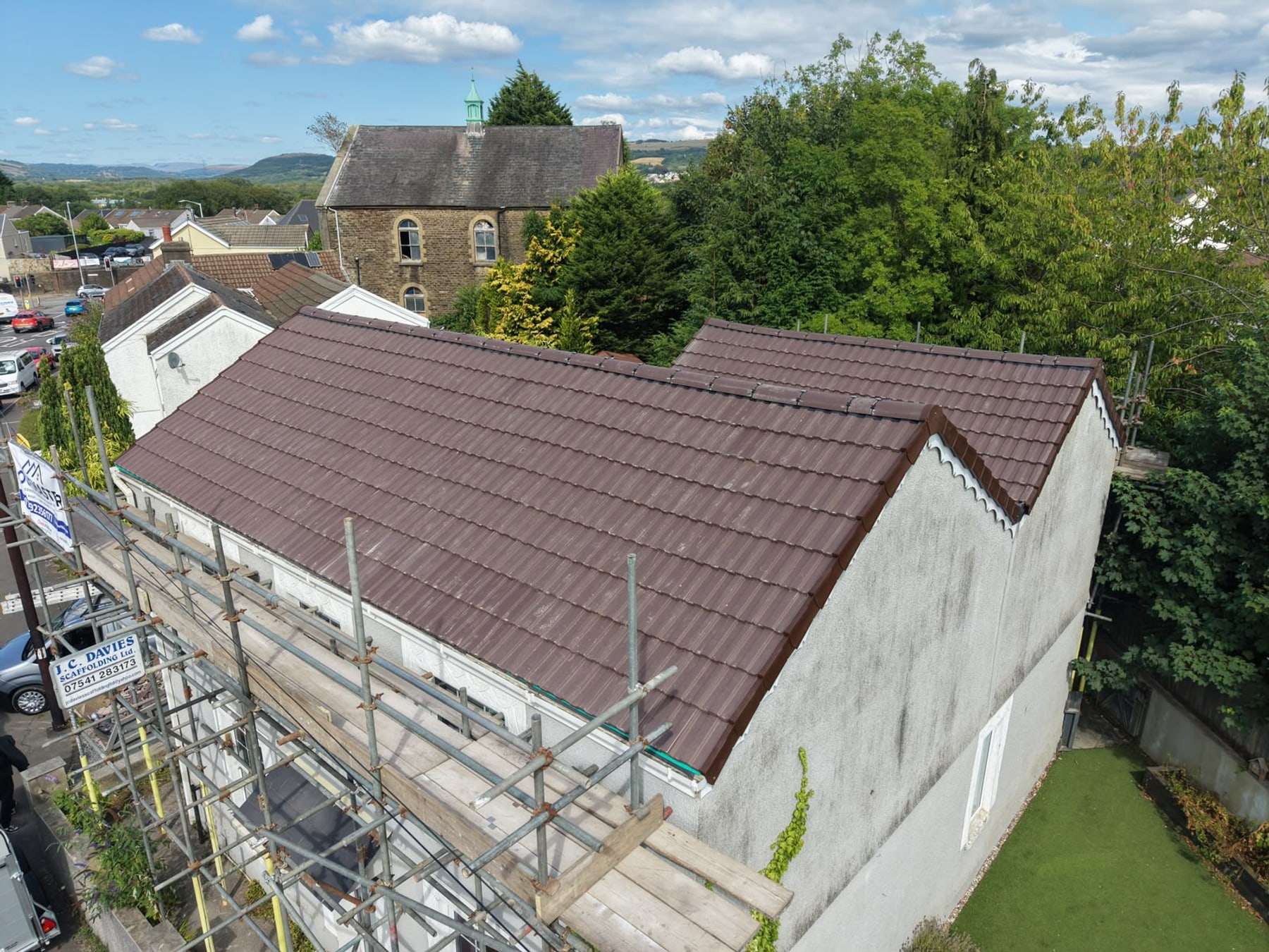 A newly tiled roof by Roofmaster with a chapel and hills behind, in the Swansea area